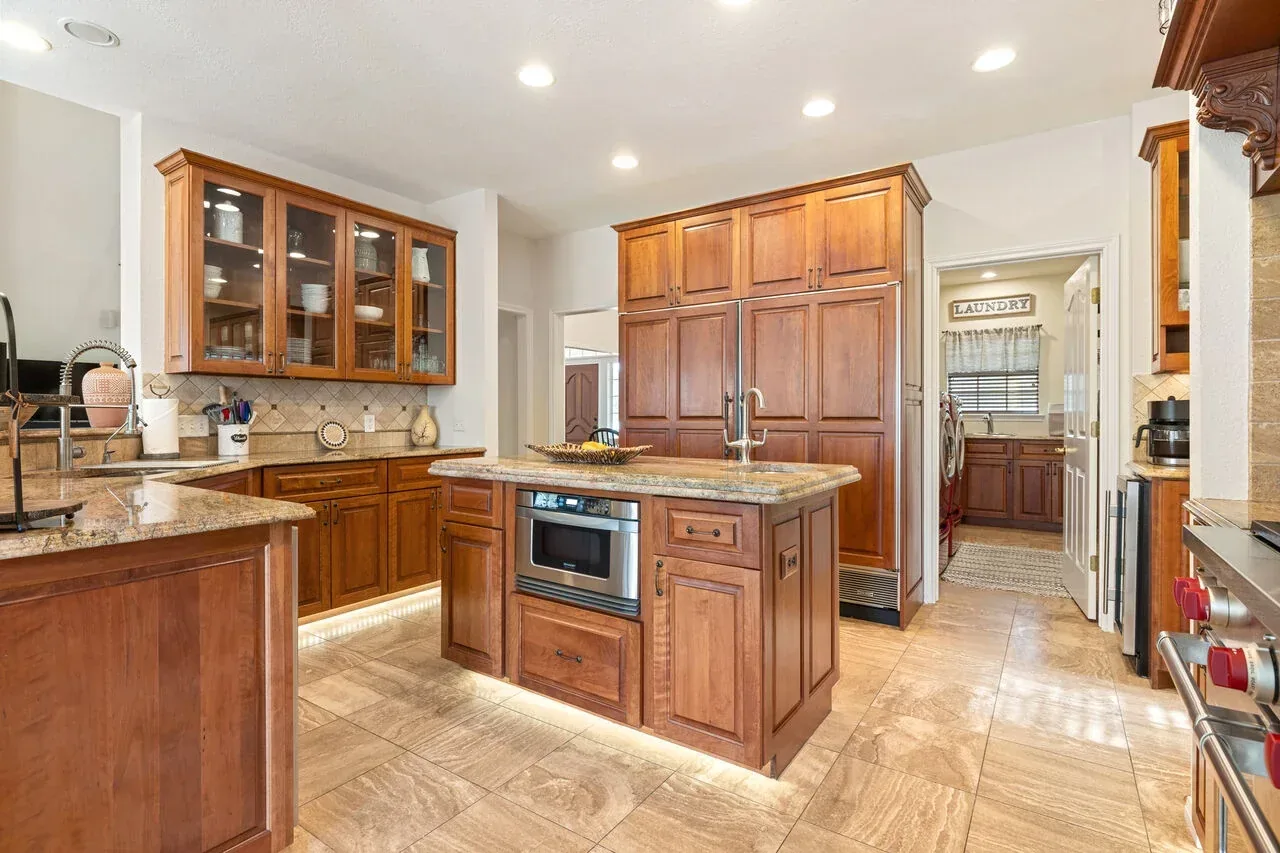 Wide Texas kitchen view with island, cabinetry, appliances, and guest-ready setup